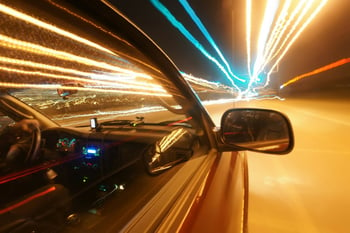 Car driving on brightly lit road