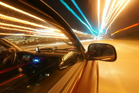 Car driving on brightly lit road